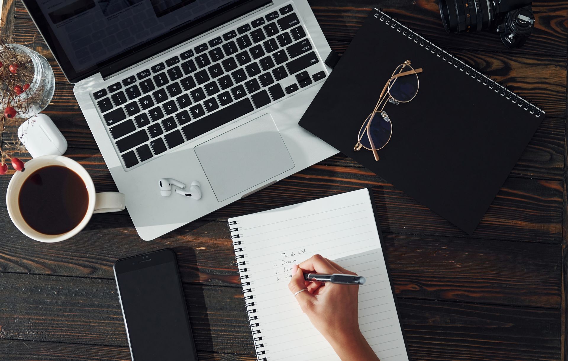 Laptop, notebook, glasses and a person writing